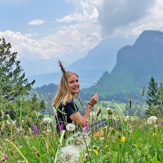 Ella-Marie in einer Blumenwiese, Berge im Hintergrund