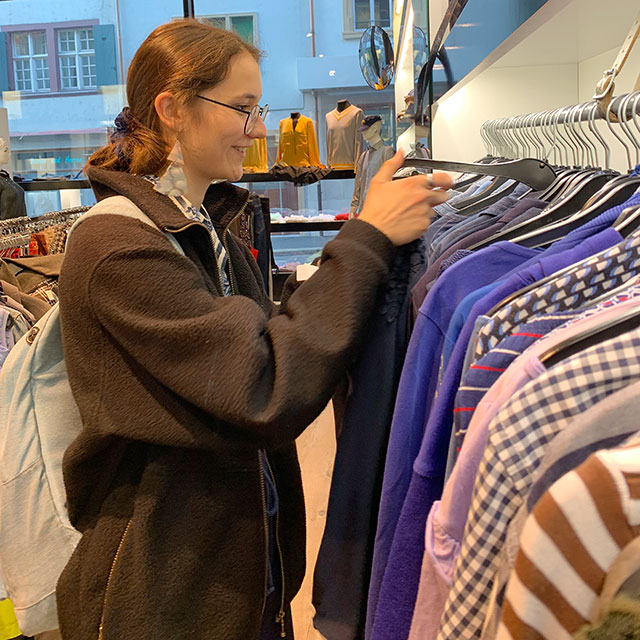 Frau schaut sich Kleider in Laden an.