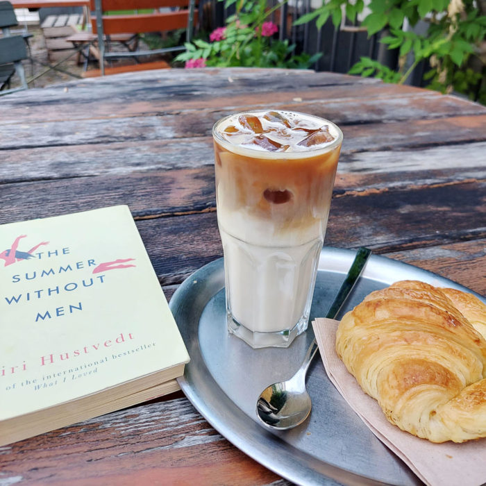 Tisch mit Buch, Kaffee und Croissant.